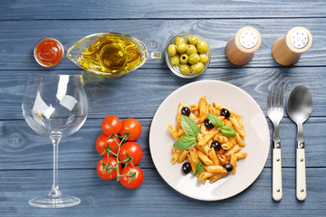 Delicious penne pasta with ingredients on wooden table