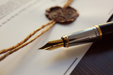 Fountain pen and old notarial wax seal on document, closeup