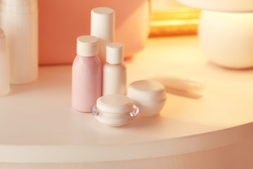 Bottles and jars with cream on white table, close up view