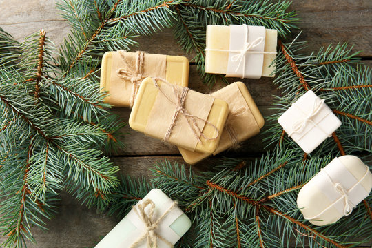Pieces of coniferous soap and branches on wooden background