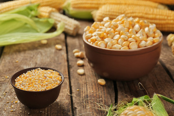 Ground corn seeds and in bowl on wooden table, closeup