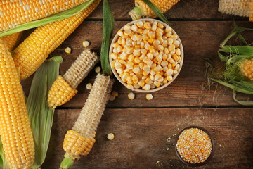 Corn seeds in bowl on wooden table, closeup