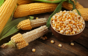 Corn seeds in bowl on wooden table, closeup