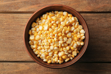 Bowl with corn seeds on wooden rustic table, closeup