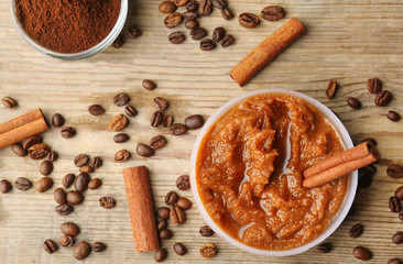 Body scrub, coffee beans and cinnamon on wooden background