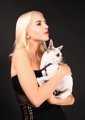 Beautiful girl holding cute dog on dark background