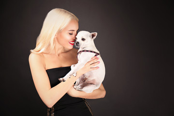 Beautiful girl holding cute dog on dark background