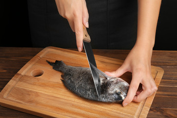 Woman cooking raw fish on kitchen
