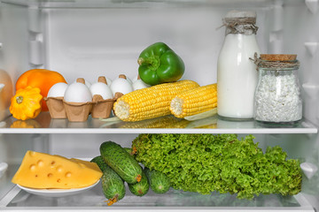 Open refrigerator full of vegetables and dairy products © Africa Studio