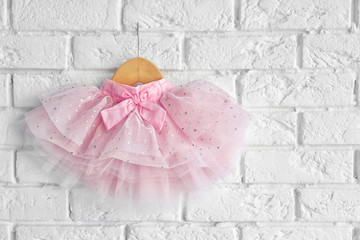 Cute pink skirt for girl hanging on white brick wall background