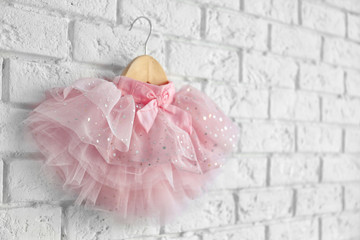 Cute pink skirt for girl hanging on white brick wall background