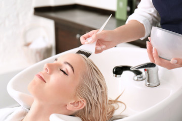 Obraz na płótnie Canvas Hairdresser putting mask on woman's hair in salon