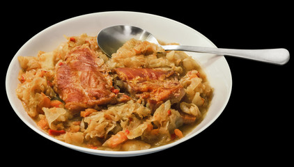 Plateful of Cabbage with Smoked Pork Ribs with Dinner Spoon Isolated On Black Background