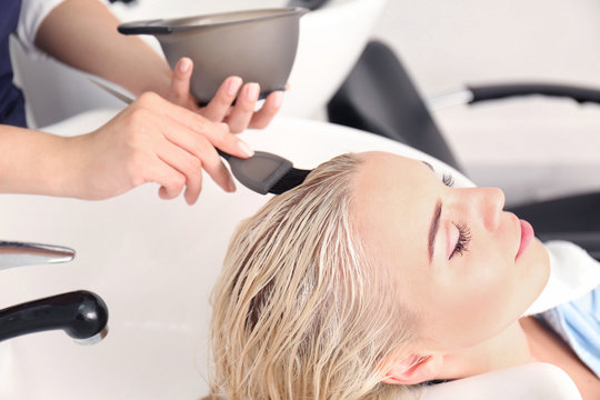 Hairdresser putting mask on woman's hair in salon