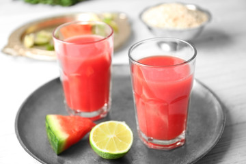 Glasses with fresh smoothie and watermelon slice on a tray