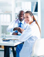 Two happy smiling young medical people handshaking at office