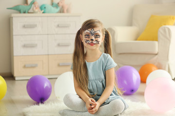 Obraz premium Funny girl with face painting sitting on floor in her room