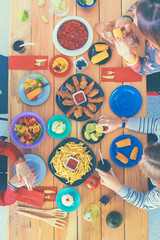 Top view group of people having dinner together while sitting at wooden table
