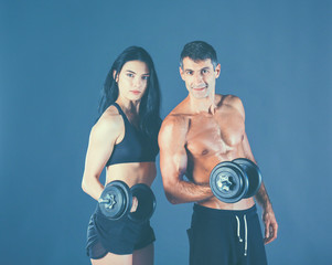 Fototapeta na wymiar Athletic man and woman with a dumbells