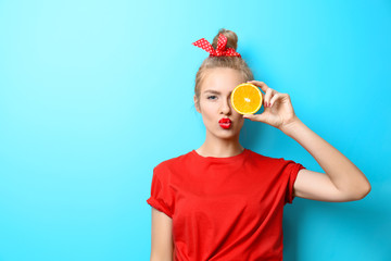 Young beautiful woman with orange on blue background
