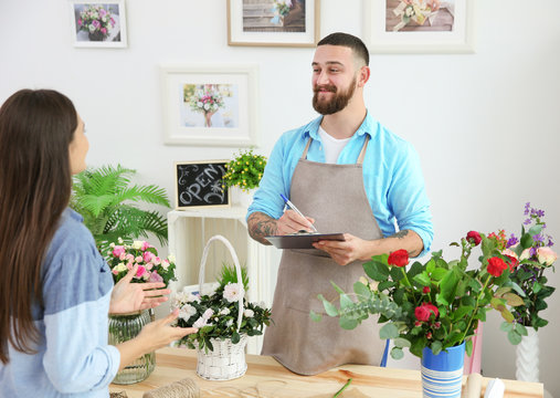 Handsome florist accepting order of young woman