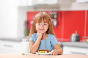 Obraz na płótnie Canvas Little girl having breakfast in the kitchen