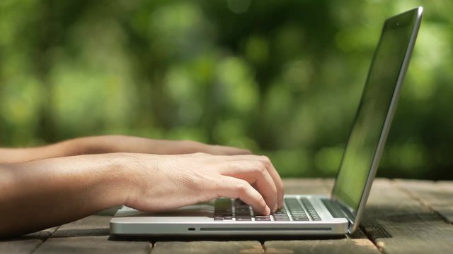 Man typing text on laptop at garden.