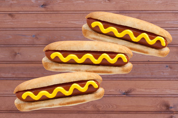 Three Hot Dogs classic with mustard  on a wooden background. American Fast Food.