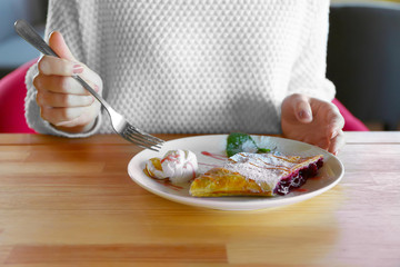 Young woman eating delicious dessert at restaurant