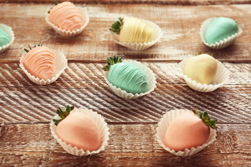 Strawberries covered with colorful chocolate icing on wooden background