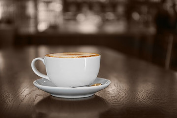 Cup with hot tasty coffee on wooden table in cafe, close up view