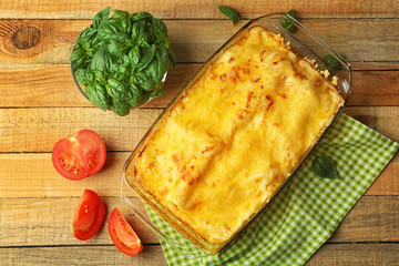 Traditional lasagna in  glass baking dish  and  napkin on wooden table