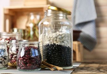Assortment of haricot beans in glass jars on kitchen table