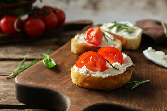 Delicious bruschetta with tomatoes on wooden board, closeup
