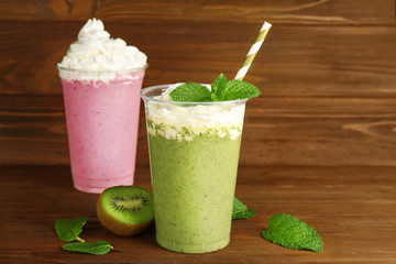 Tasty fruit cocktails with cream on wooden background