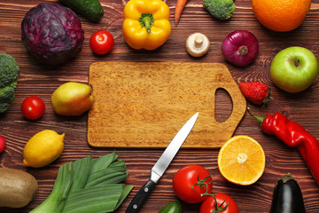 Set of fresh vegetables and fruits with cutting board on wooden background