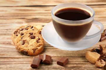 Tasty chocolate cookies with cup of hot coffee on wooden background