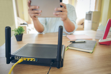 closeup of a wireless router and a man using  Tablet on living room at home ofiice - obrazy, fototapety, plakaty