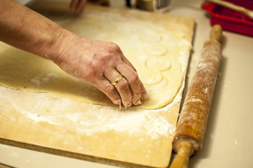 preparare i biscotti di natale con farina uova zucchero e marmellata con il mattarello