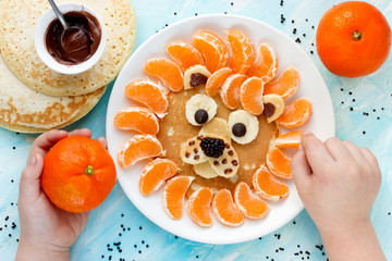 Child cooking and eating funny breakfast lion pancake