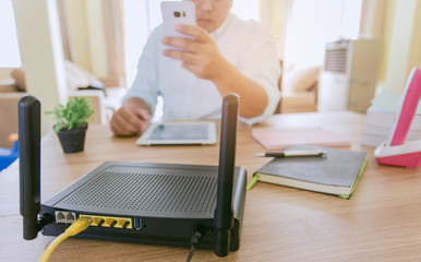 closeup of a wireless router and a man using smartphone on living room at home ofiice