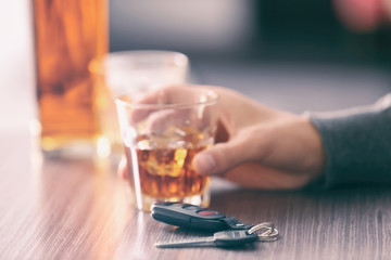 Man sitting in bar with alcoholic beverage and car key, closeup. Don't drink and drive concept