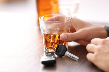 Man sitting in bar with alcoholic beverage and car key, closeup. Don't drink and drive concept