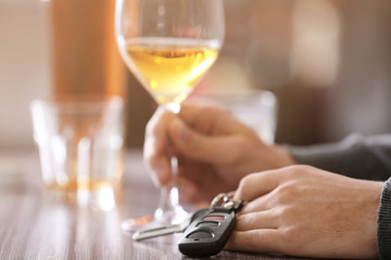 Man sitting at table with car key and glass of alcoholic beverage, closeup. Don't drink and drive concept