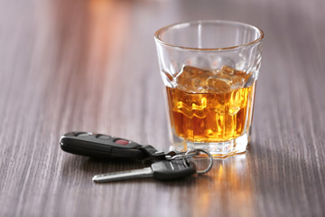 Glass with alcoholic beverage and car key on wooden table. Don't drink and drive concept