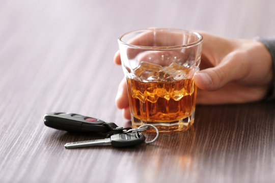 Man sitting in bar with alcoholic beverage and car key, closeup. Don't drink and drive concept