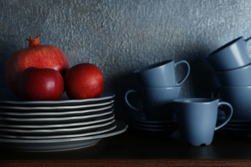 Set of dinnerware and fruits on gray background