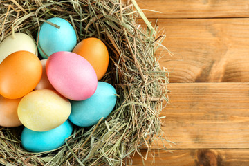 Nest with colorful Easter eggs on wooden table, closeup