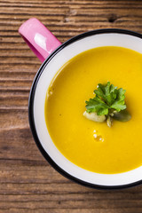 Pumpkin soup in enamel mug, with pumpkin seeds and parsley, clos