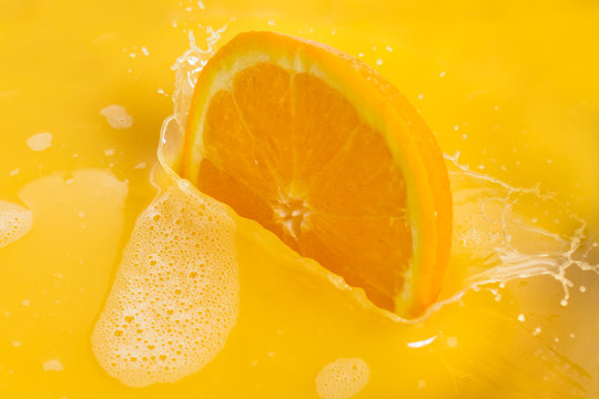 Orange Slices Splashing into Orange Juice on White Background